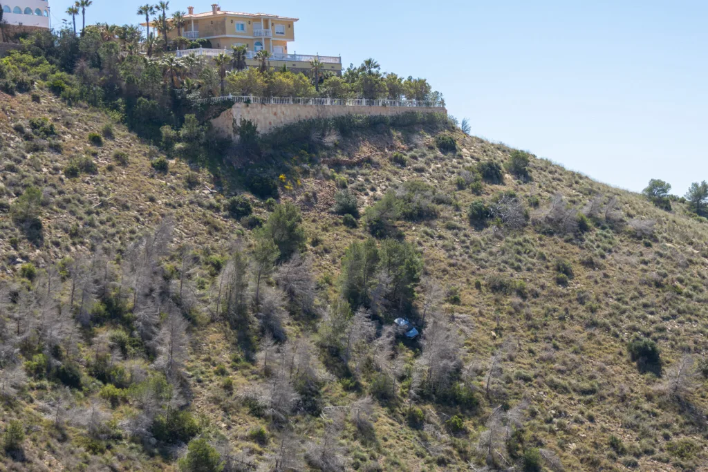 White car crashed and fallen down a steep slope in a hilly area 1 1